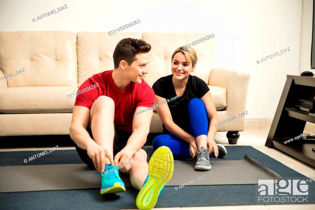 Stock Photo: Hispanic young couple tying their shoes and about to begin their workout at home.
