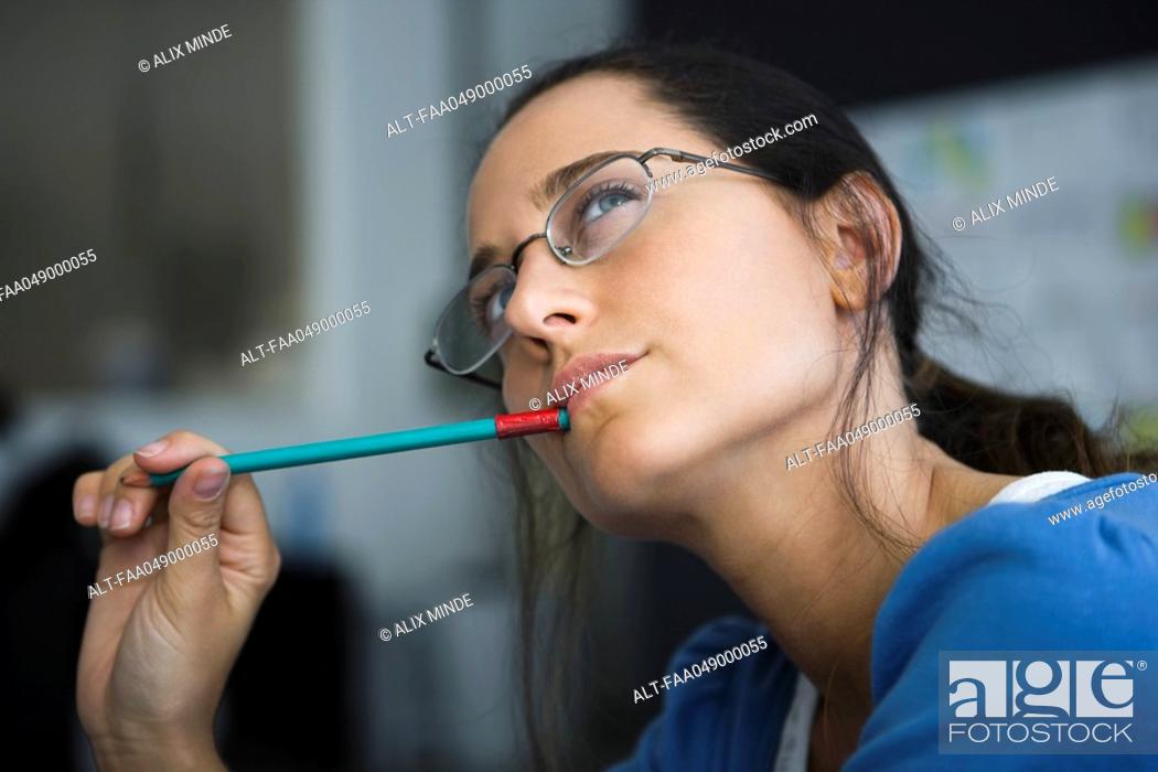 Stock Photo: Woman thinking, looking away, pen in mouth.