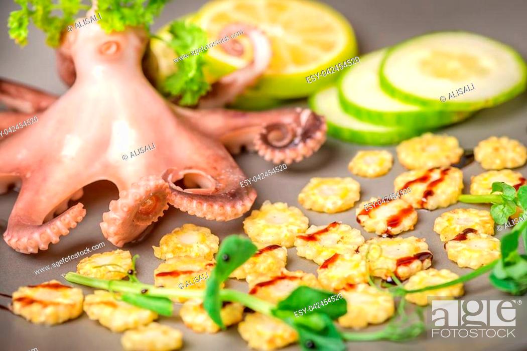 Photo de stock: close up of octopus served with lime, corn, cucumber and sprig of pea leaves on plate.