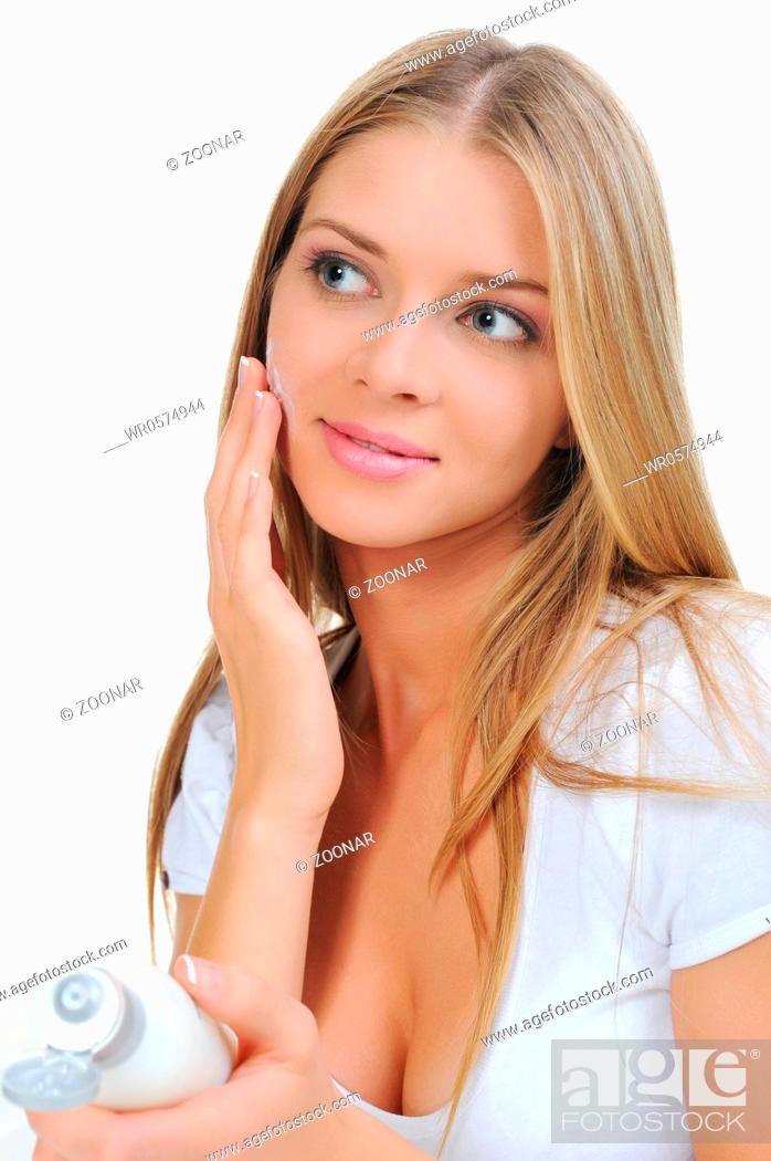 Stock Photo: beautiful woman applying cream on her cheek.