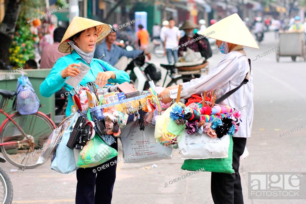 Stock Photo: Female street vendor carries two baskets of various things in baskets, food, fresh fruit, flower and etc for sell, Hanoi, Vietnam.