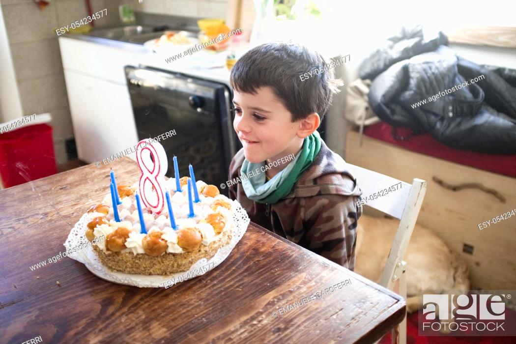 Photo de stock: child turns eight years and blows out the candles of the cake.
