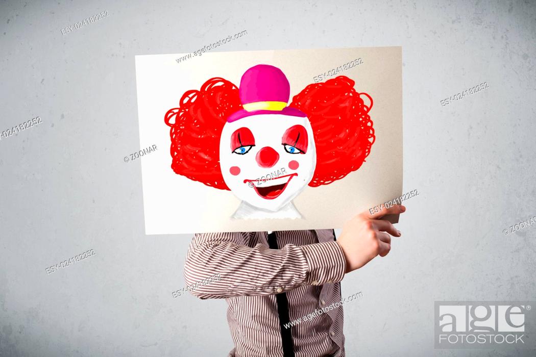 Imagen: Businessman holding a cardboard with a clown on it in front of his head.