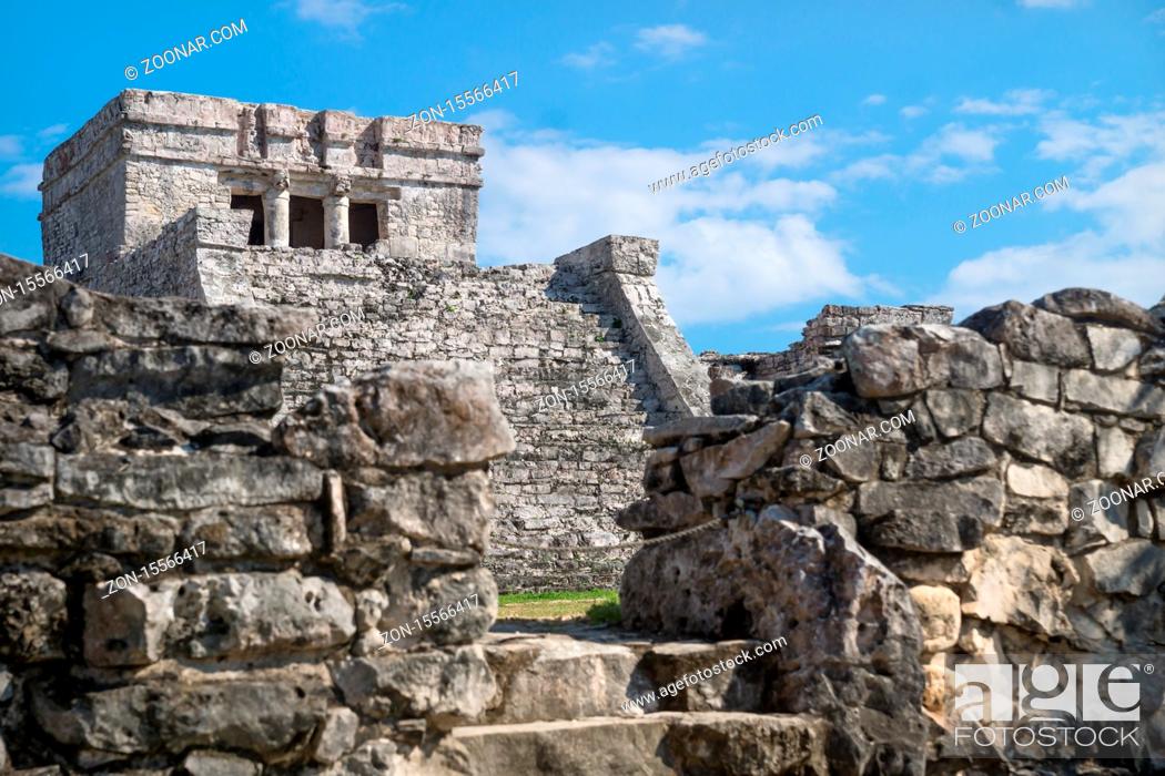 Stock Photo: El Castillo Maya ruins behind blurred wall with blue sky, Tulum, Mexico.