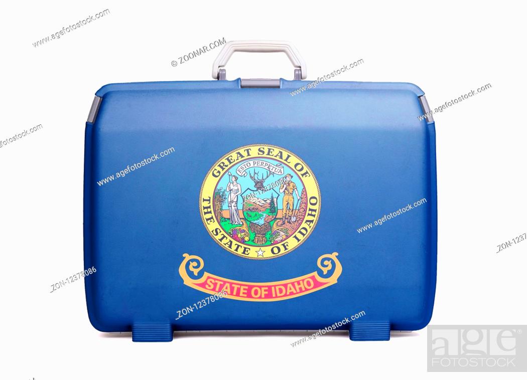 Stock Photo: Used plastic suitcase with stains and scratches, printed with flag, Idaho.
