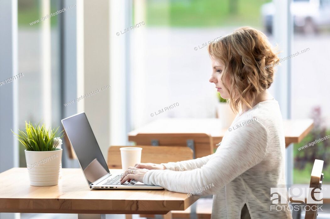 Stock Photo: A professional business woman working on a computer in a coffee shop: Edmonton, Alberta, Canada.