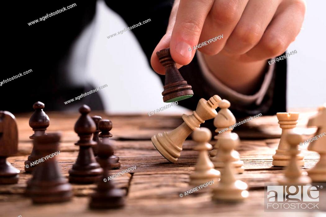 Stock Photo: Close-up Of A Businessperson Checkmating King Chess Piece With Rook On Wooden Desk.