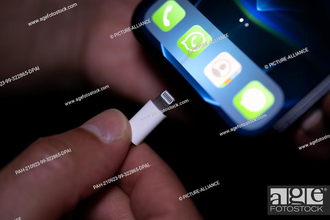 Stock Photo: 22 September 2021, Lower Saxony, Oldenburg: A Lightning charging plug is inserted into an Apple iPhone. The EU Commission presents a proposal for a uniform.