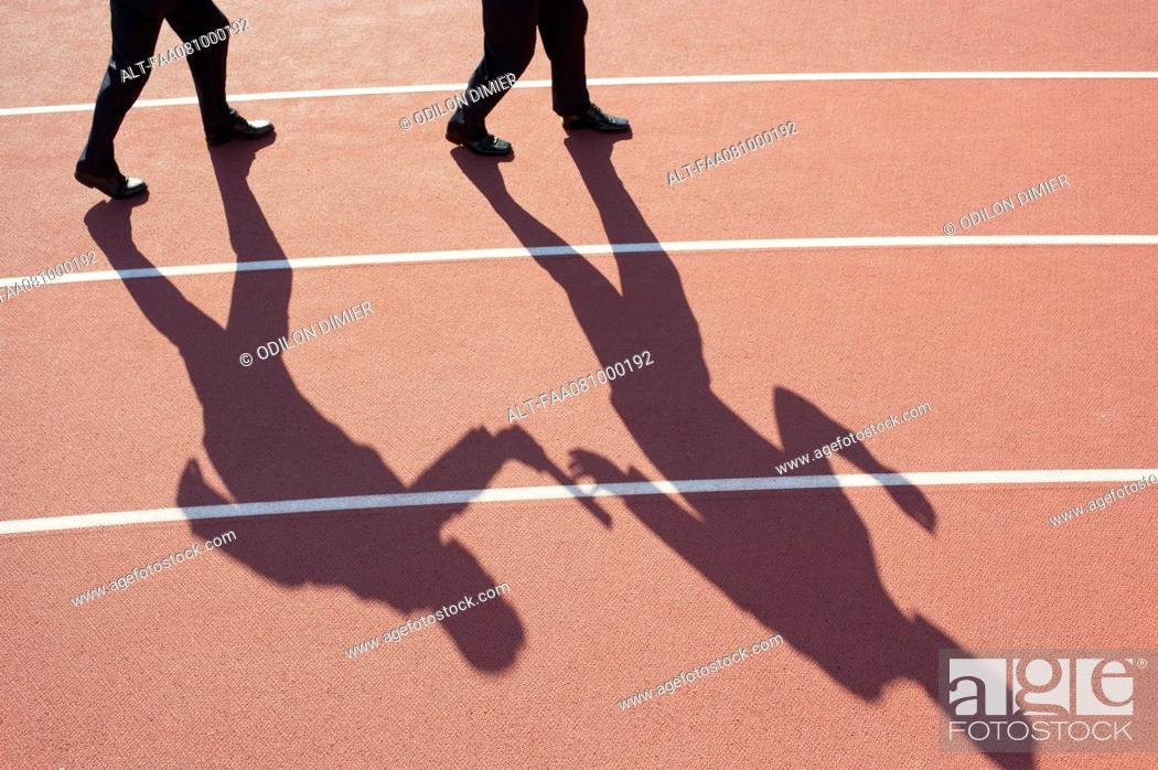 Stock Photo: Shadow of men passing baton on running track.