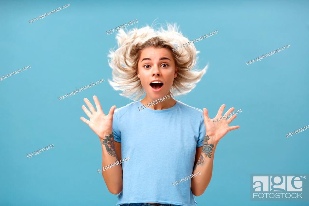 Stock Photo: Waist-up shot of impressed surprised attractive and cute girl with blonde hair floating in air and tattooed arm jumping with spread raised palms and opened.