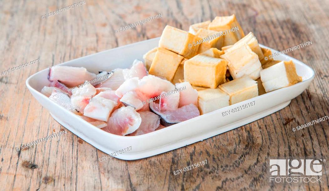 Stock Photo: Meat, fish and tofu dish in white placed on a wooden table. Focus on fish.