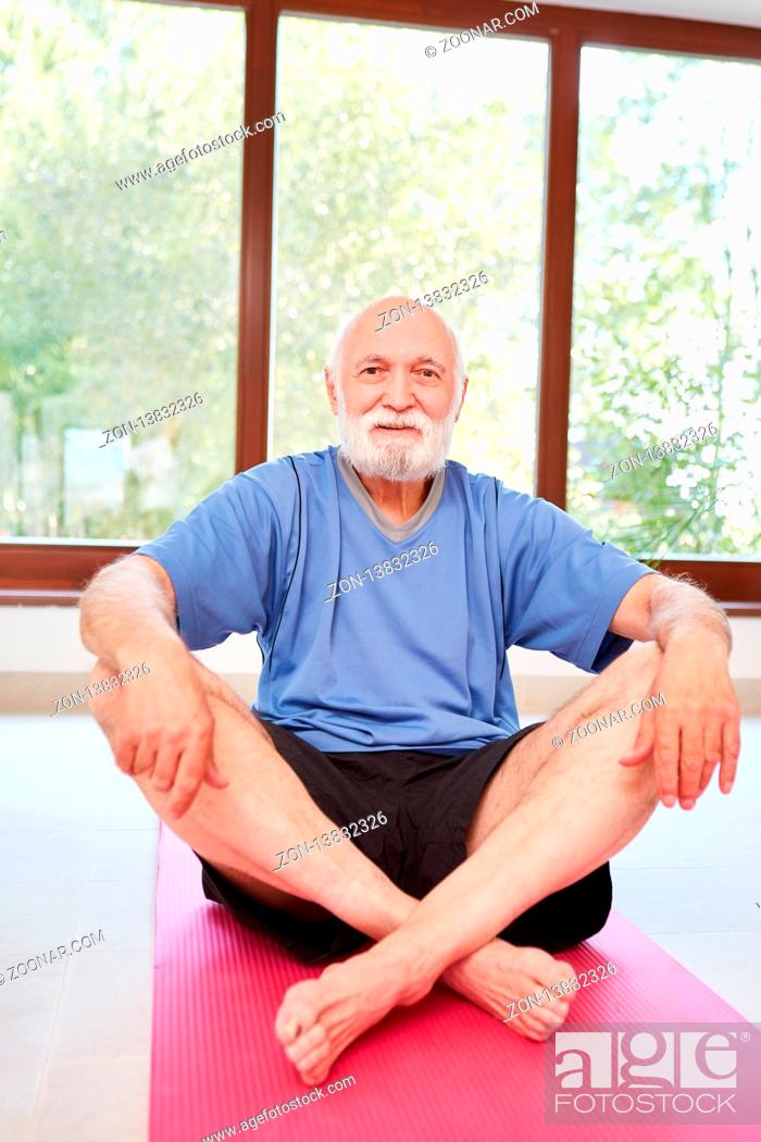 Stock Photo: Vitaler Senior Mann sitzt entspannt auf eine Yoga Matte im Fitnesscenter.