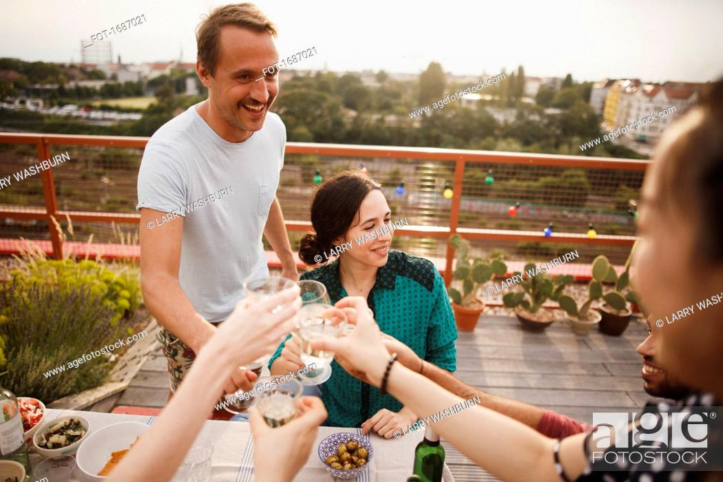 Stock Photo: Happy male and female friends toasting wineglasses on patio.