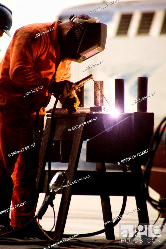 Stock Photo: An arc welder makes a repair in a Los Angeles, CA, railroad yard. Note train in background.