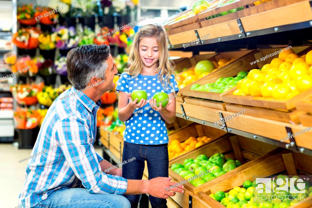 Stock Photo: Smiling father giving apples to his cute daughter in grocery shop.