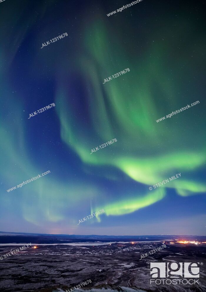 Stock Photo: The aurora borealis glows over the Delta River and the distant lights of Fort Greely and Delta Junction, Interior Alaska, USA.