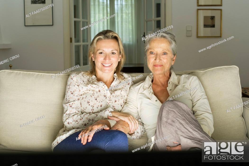 Stock Photo: Mother and daughter watch TV in living room.