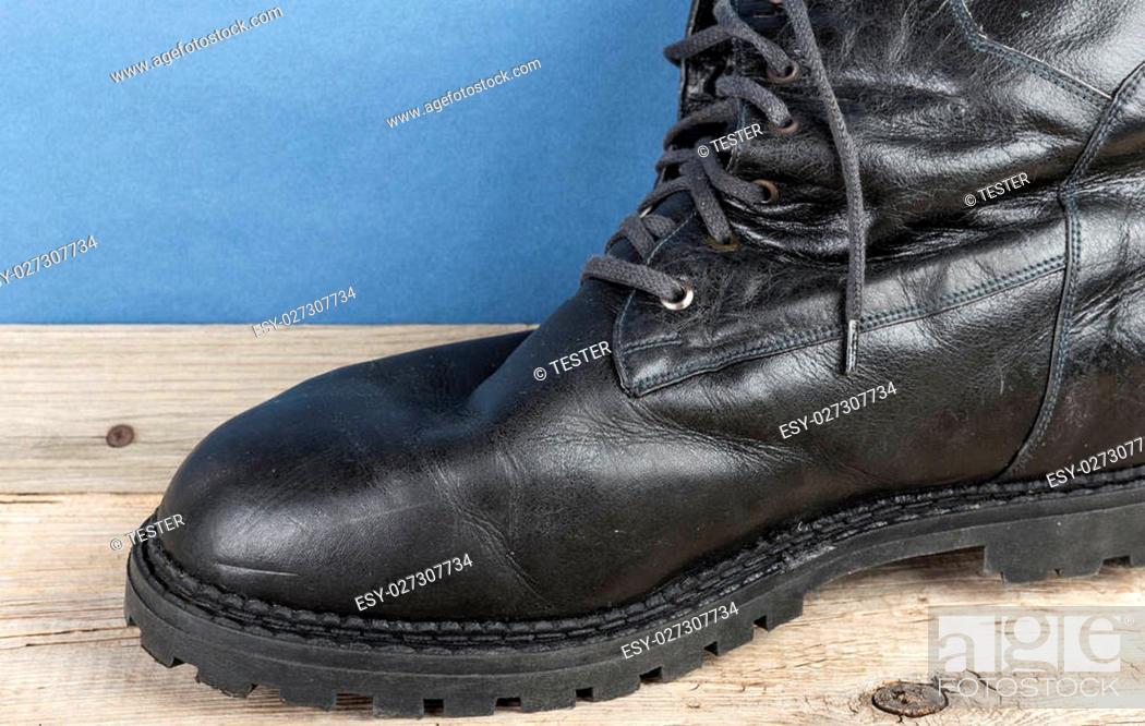 Stock Photo: Black army boot against the wall.