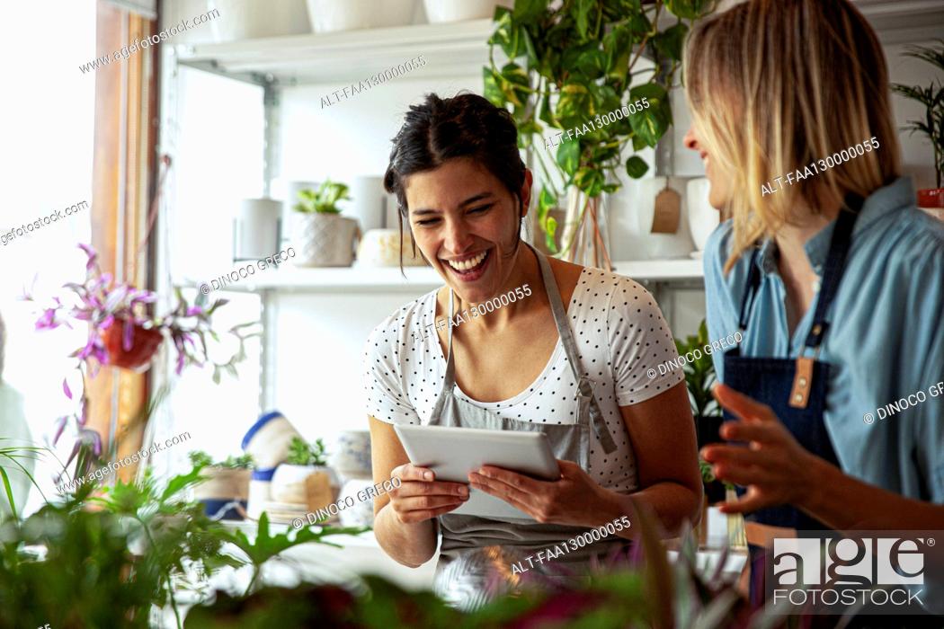Stock Photo: Cheerful flower shop female owners holding digital tablet.