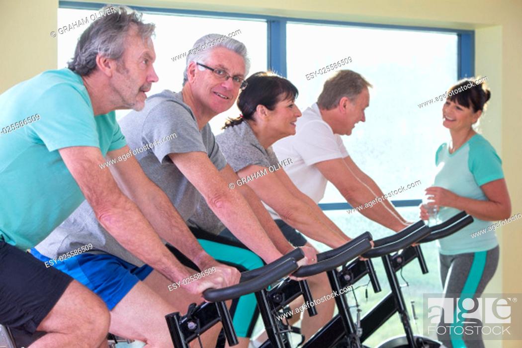 Stock Photo: A group of seniors using the spinning bikes at the gym.