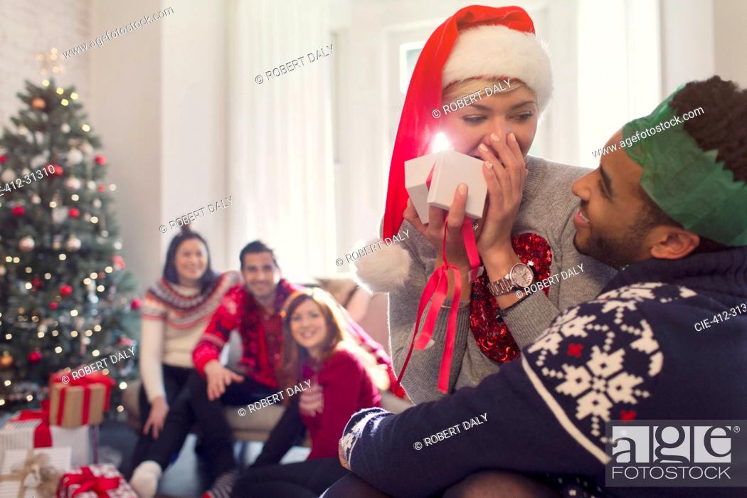 Stock Photo: Surprised girlfriend opening Christmas gift from boyfriend.
