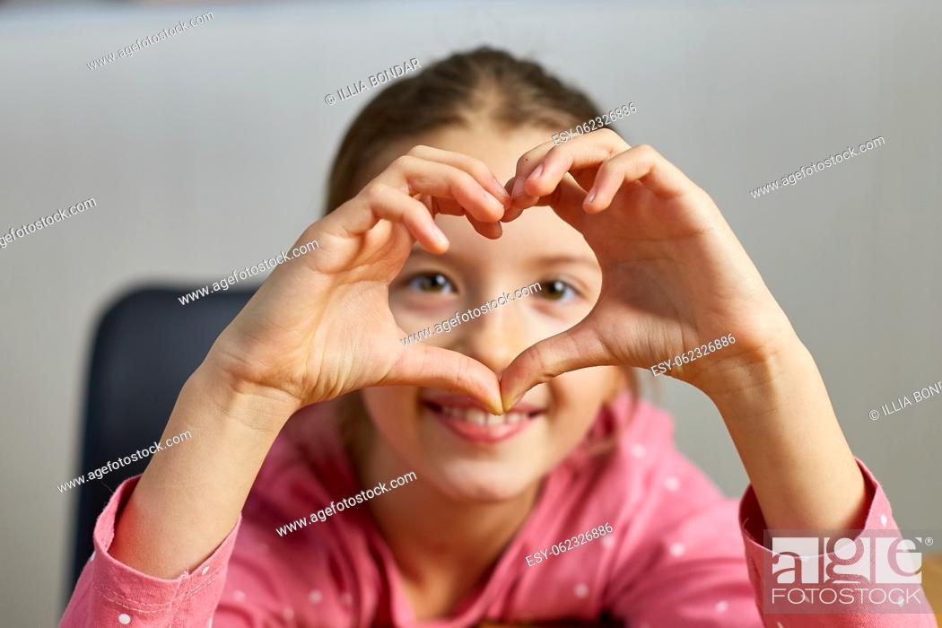 Stock Photo: Little girl, making hearts from hands, love, casual cheerful cute funny girl showing heart shape sign with fingers.