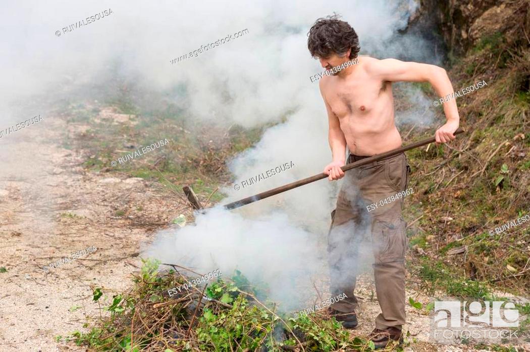 Stock Photo: Work in the farm. Farmer burning dried branches.