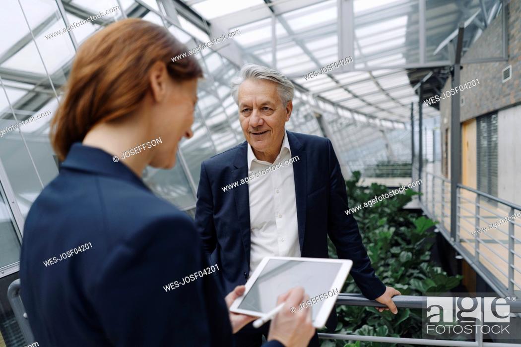 Stock Photo: Smiling businessman and businesswoman with tablet in modern office building.