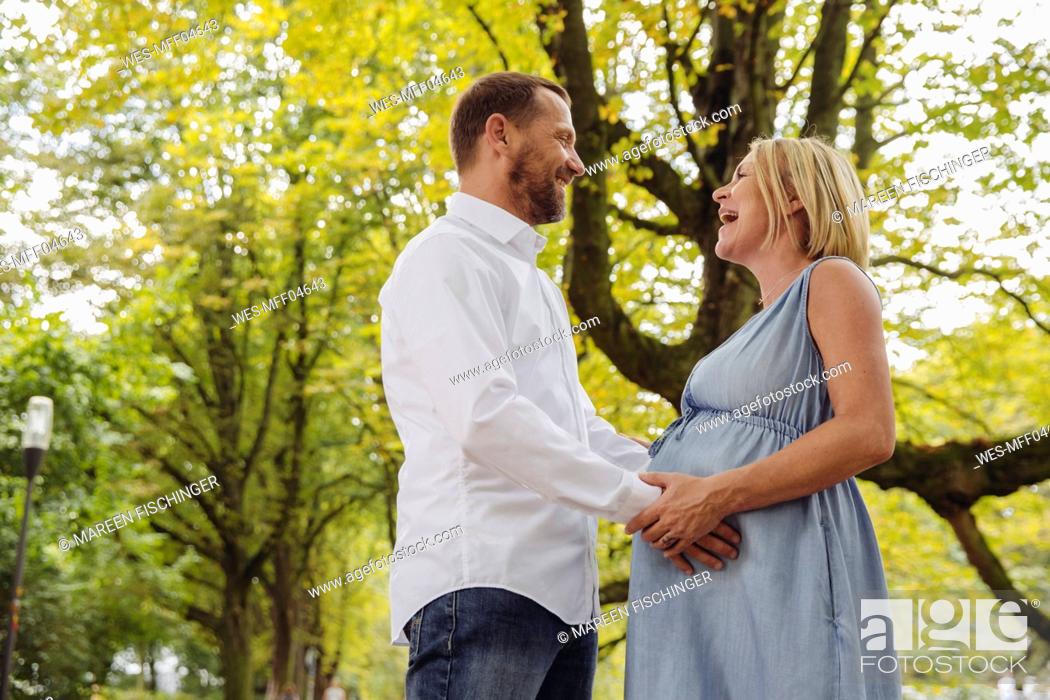 Stock Photo: Happy mature pregnant couple talking in park.