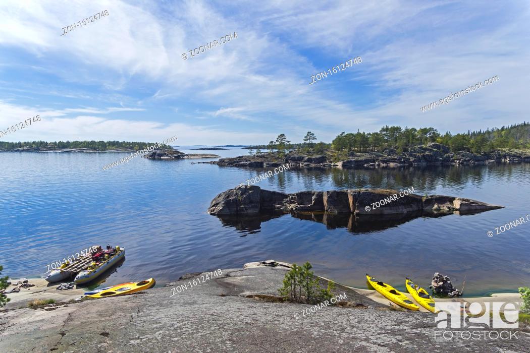 Stock Photo: Tourist catamaran and kayaks at the granite shore. Ladoga skerries, Karelia, Russia. Sunny day in early June.