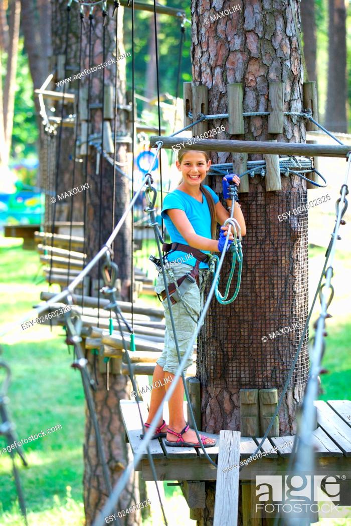Stock Photo: Happy school girl enjoying activity in a climbing adventure park on a summer day.