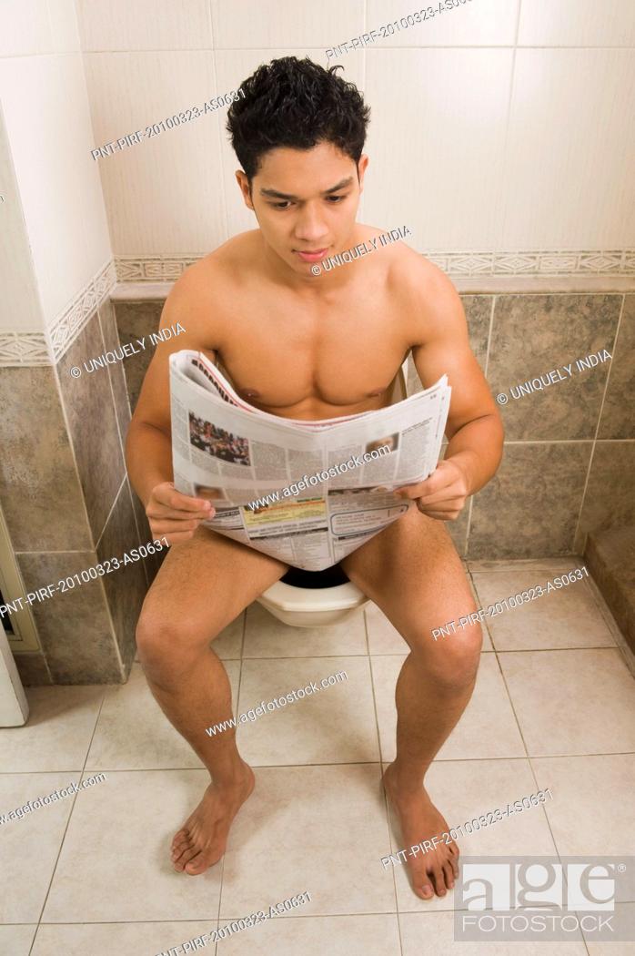 Portrait Of A Young Man Sitting On A Toilet Using A Laptop 