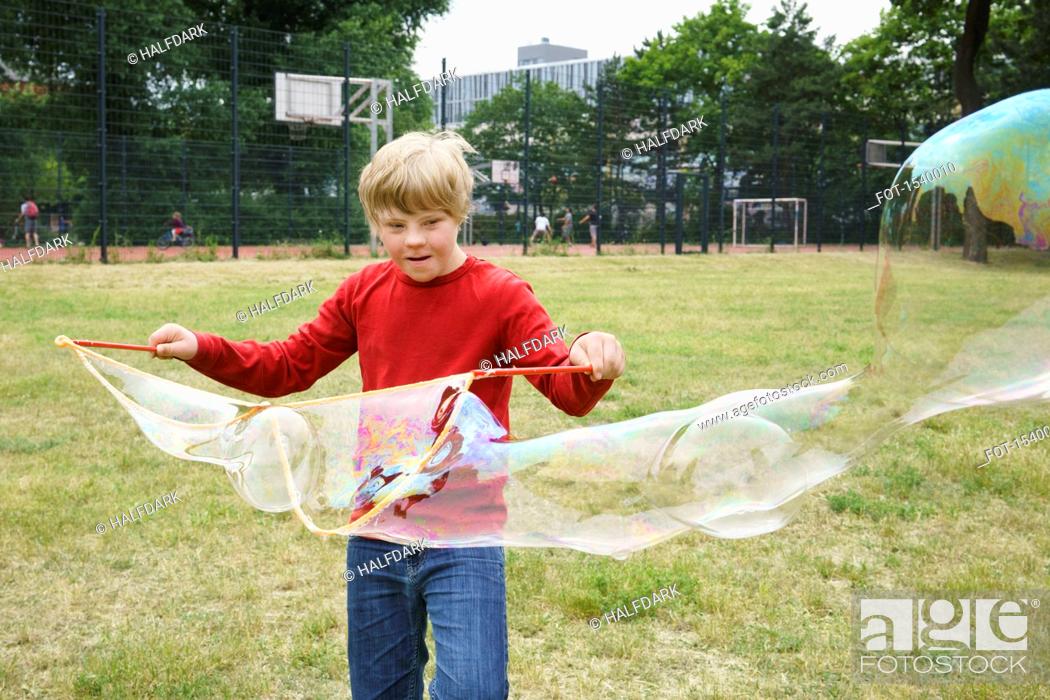 Stock Photo: Boy playing with soap bubbles in park.