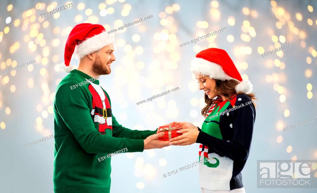 Stock Photo: happy couple in ugly sweaters with christmas gift.