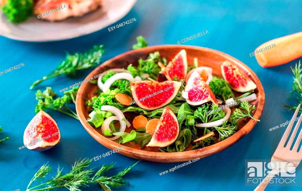 Stock Photo: Autumn salad of arugula, figs in brown earthenware plate on a blue background. top view.