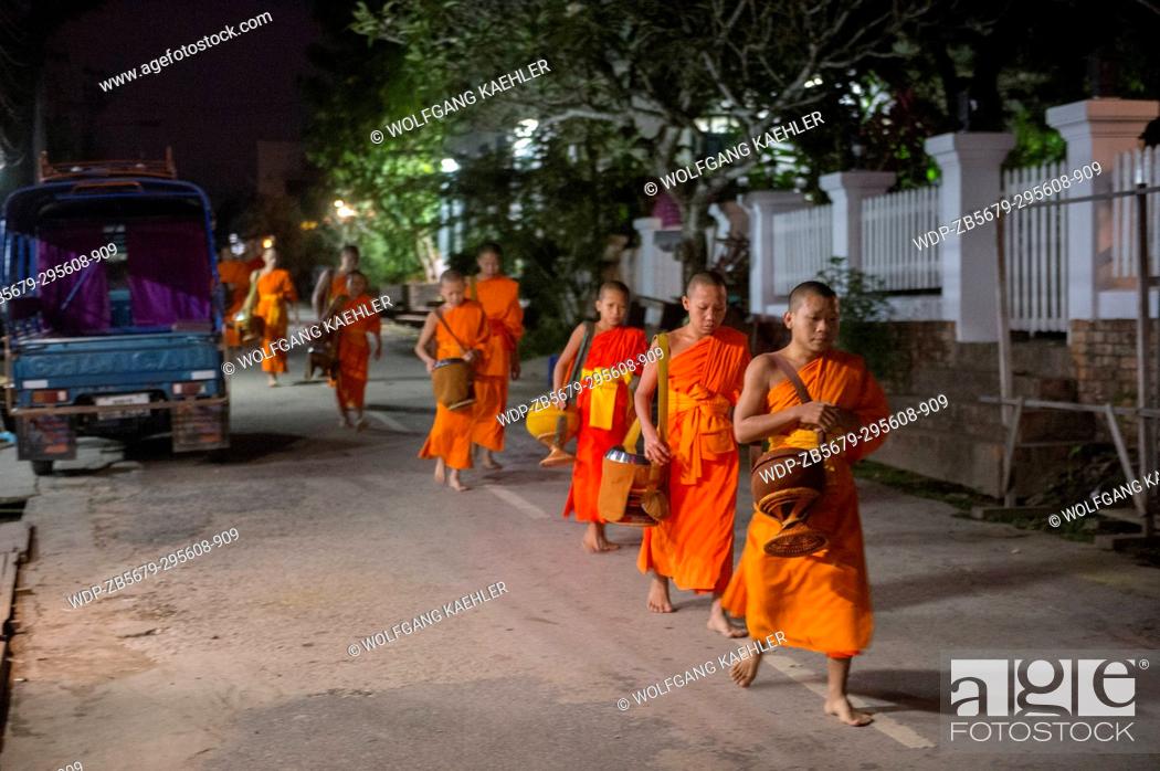 Stock Photo: Buddhist monks gathering to receive alms in the early morning before sunrise from the people of the UNESCO world heritage town of Luang Prabang in Central Laos.