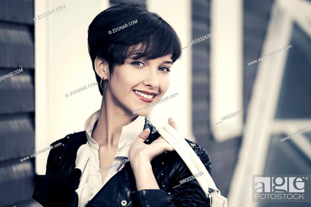 Stock Photo: Happy young fashion woman in leather jacket with handbag.
