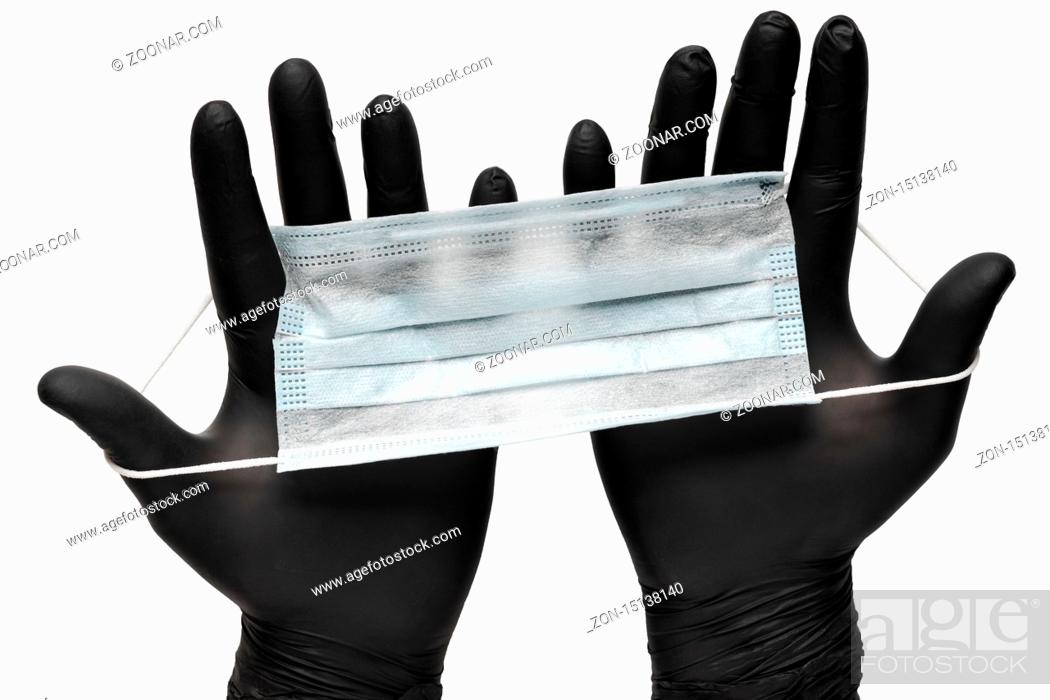 Stock Photo: Medical man holds antivirus face mask in hands in black medical gloves. Isolated on white background. Pandemic insurance, airborne diseases, SARS, grippe.