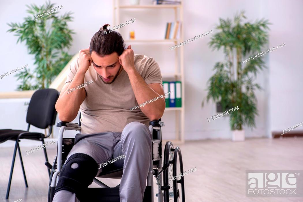 Stock Photo: Young leg injured man in the wheel-chair.
