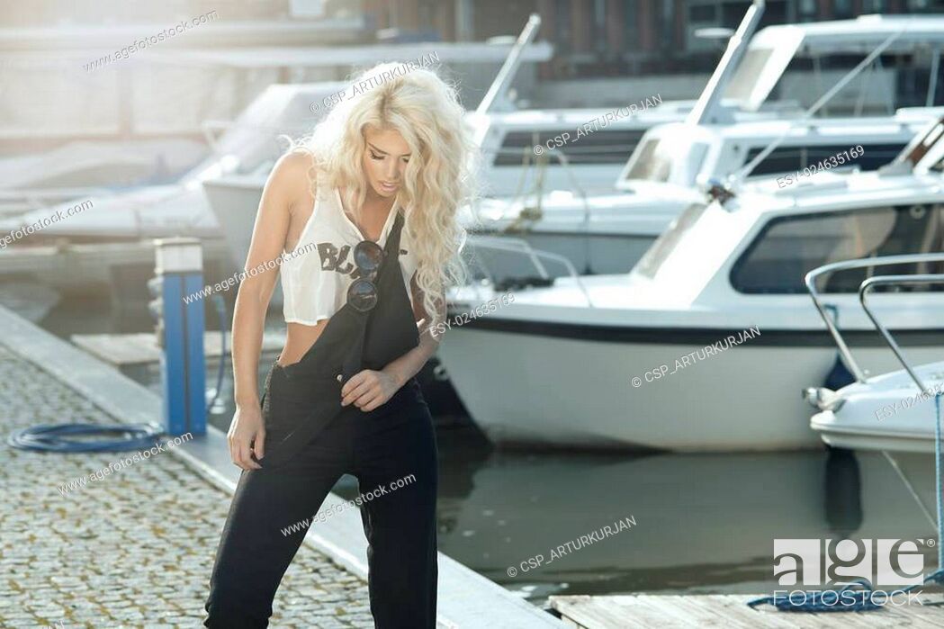 Stock Photo: Stylish woman in dungarees standing on marina.