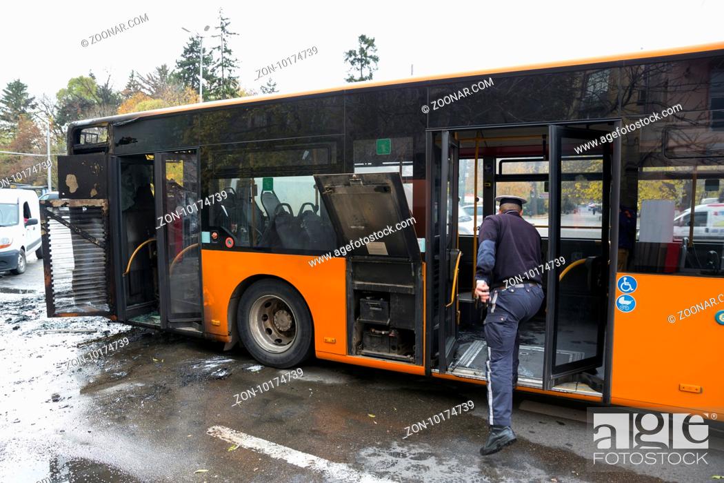 Stock Photo: Burnt public traffic bus is seen on the street after caught in fire during travel and extinguished by firefighters.