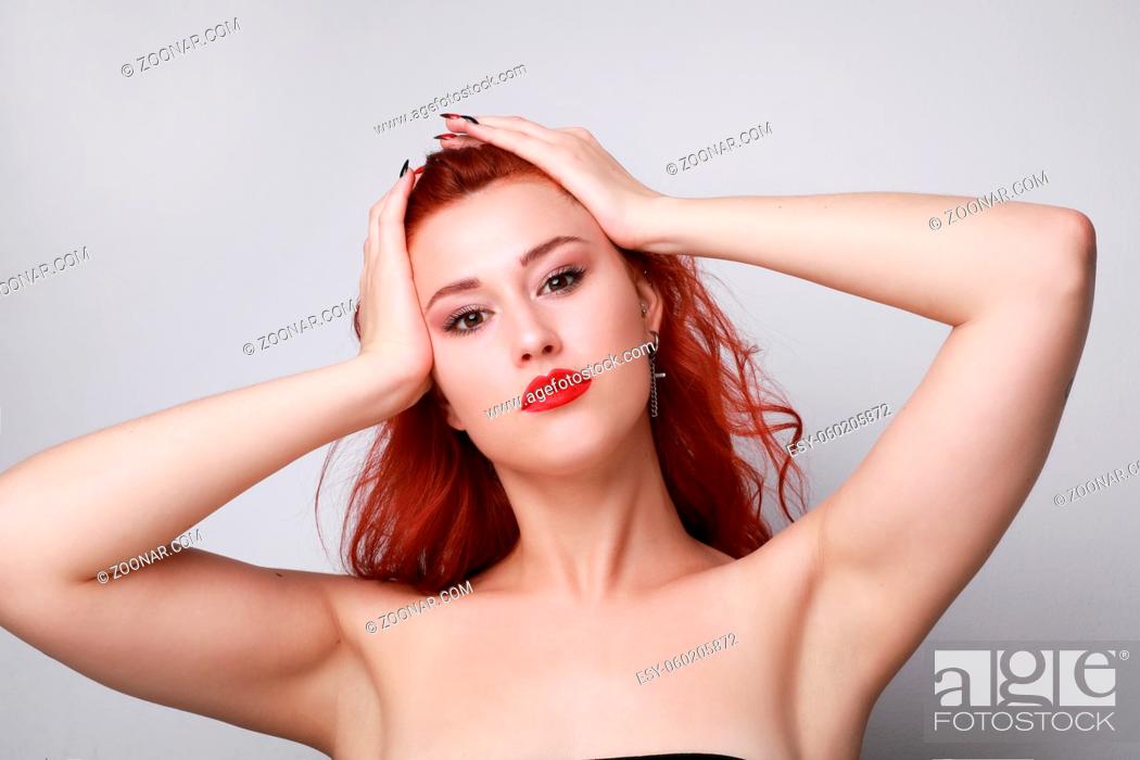 Stock Photo: Young woman with red hair posing over grey background. High quality photo.