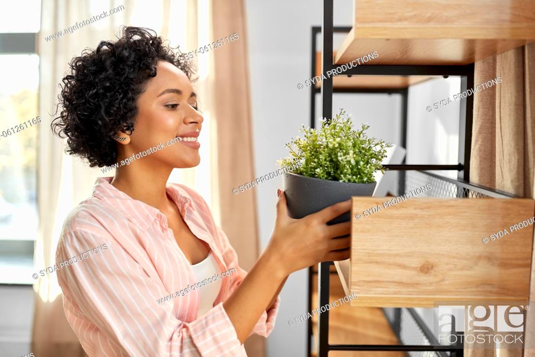 Stock Photo: woman decorating home with flower or houseplant.