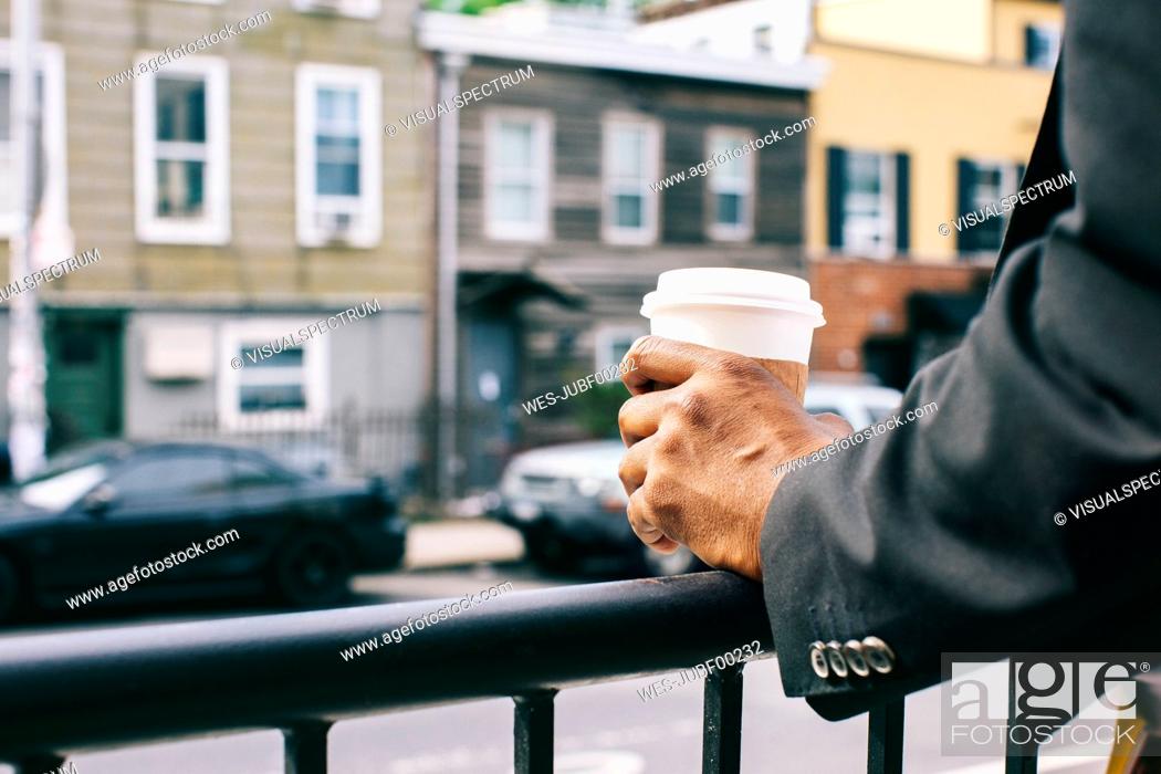 Imagen: Hands of a man holding cup of coffee on railing.