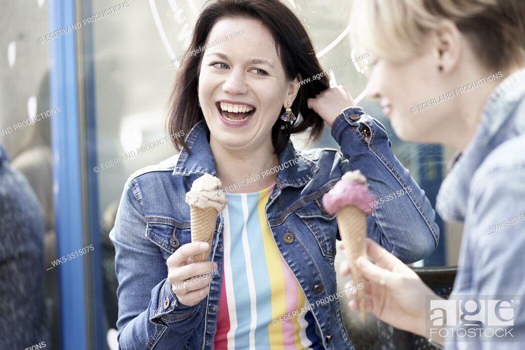Stock Photo: Two happy female friends eating vegan dairy-free and sugar-free ice cream cone made with cashew nuts and dates.