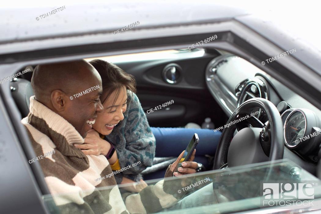 Stock Photo: Happy couple using smart phone in car window.