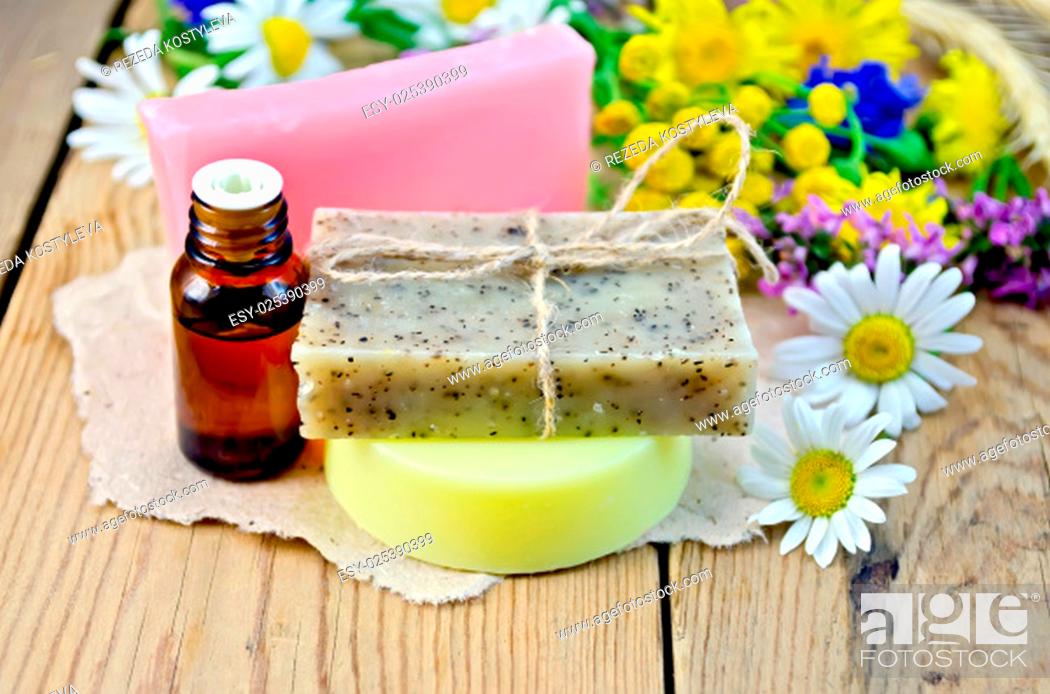 Photo de stock: Oil in a bottle, homemade soap on a piece of paper, chamomile flowers, tansy, elecampane on the background of wooden boards.