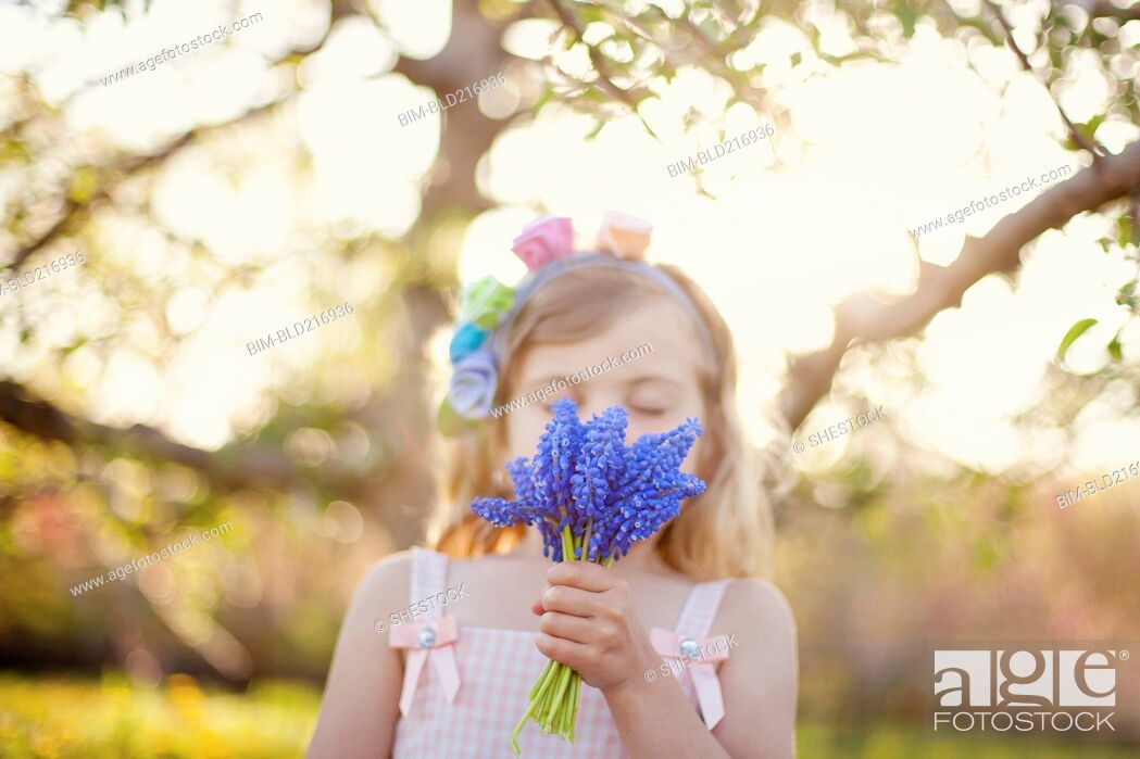 Stock Photo: Caucasian girl smelling flowers outdoors.