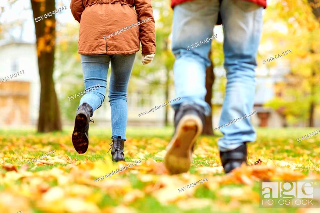 Stock Photo: love, relationships, season and people concept - young couple running in autumn park.