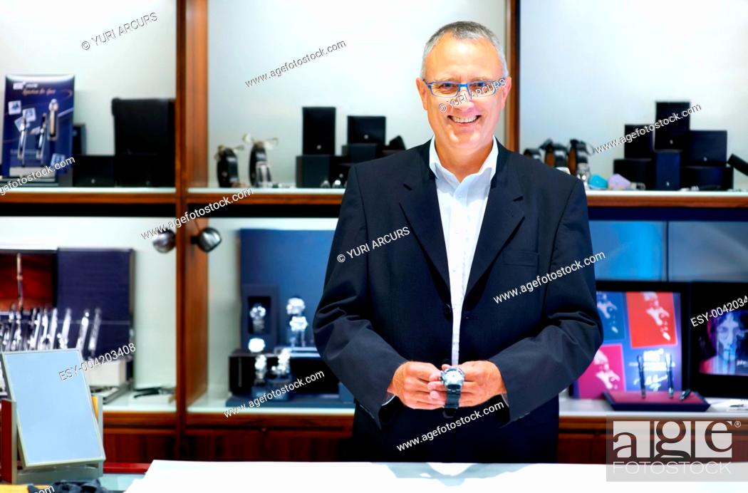 Stock Photo: Mature jewllery store clerk smiling while holding a wristwatch - portrait.